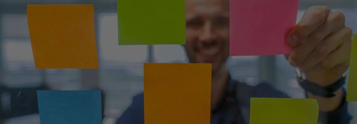 Dario klebt farbige Post-It an die Glaswand.