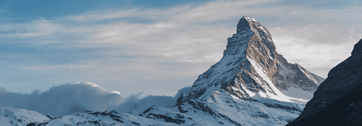 Schneebedecktes Matterhorn bei klarer Winterstimmung, umgeben von Wolken und blauen Himmel.