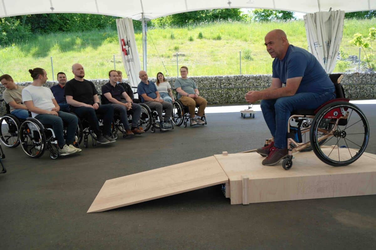 Einheits-Akrtionstag-schweizer-paraplegiker-zentrum_1 Eine Person im Rollstuhl spricht vor mehreren Teilnehmenden, die ebenfalls im Rollstuhl sitzen.
