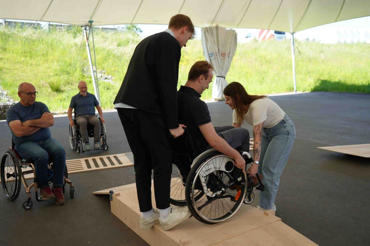 Einheits-Akrtionstag-schweizer-paraplegiker-zentrum_3 Sandro und Whitney helfen Robin im Rollstuhl die Rampe herunterzukommen.
