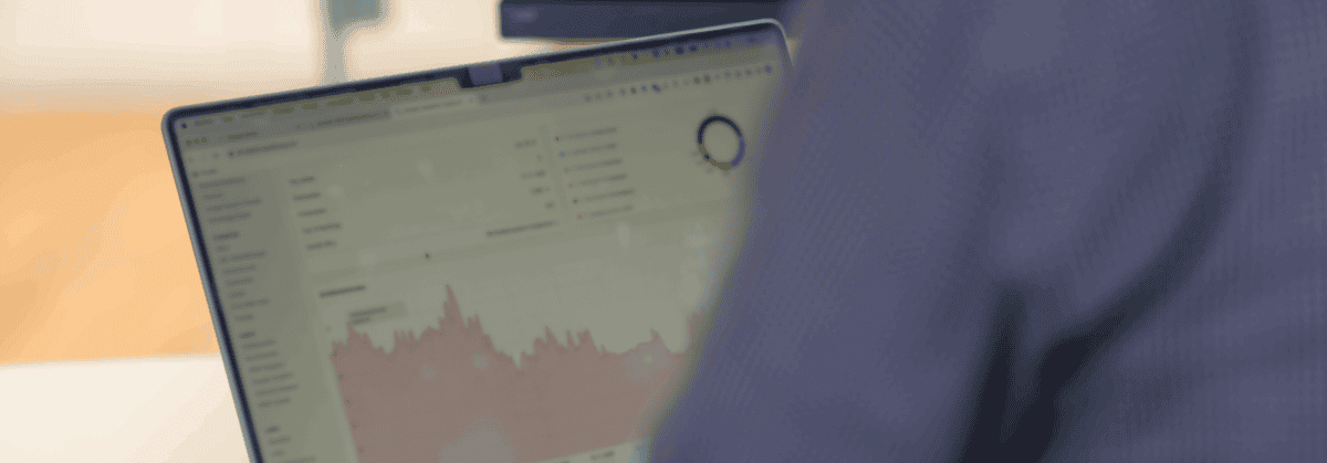 Eine Person arbeitet an einem Laptop, auf dessen Bildschirm ein Dashboard mit Diagrammen und Statistiken zu sehen