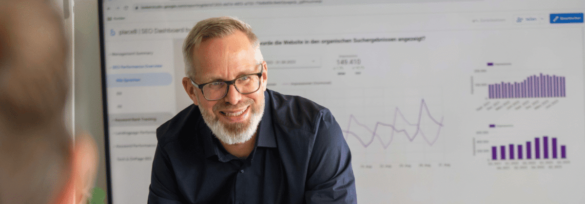 Bruno während einer Besprechung. Im Hintergrund ist ein grosser Bildschirm mit Diagrammen und Statistiken.