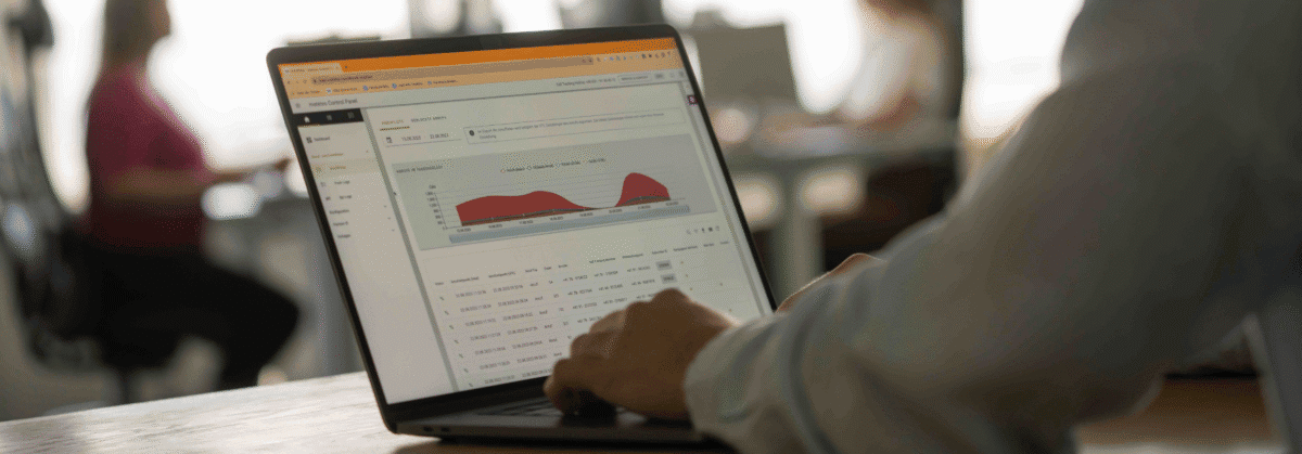 Eine Person arbeitet am Laptop und auf dem Laptop sind Statistiken zusehen.