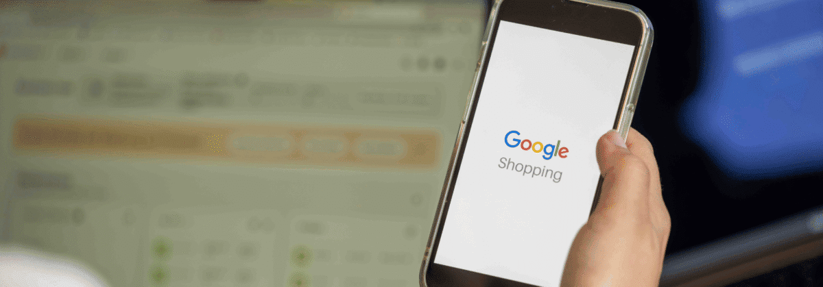 Nahaufnahme einer Hand, die ein Handy mit der Google-Shopping-Startseite hält.